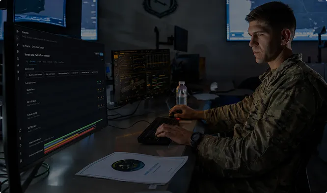 An analyst reviewing mission dashboards at a multi-screen workstation.